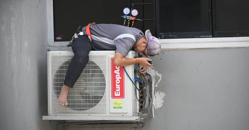 Deux employés en gilets de sécurité et casque qui discutent au dessus d'un toit de bâtiment sur les condenseurs en toiture à l’épreuve de la chaleur